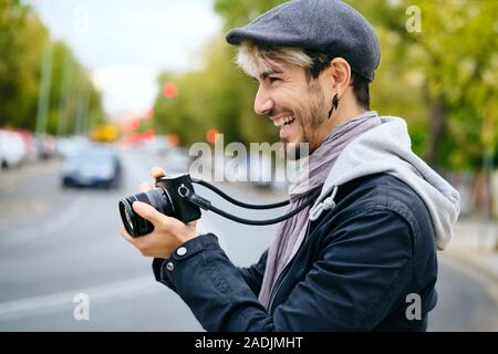 Hipster fotografo tenendo Street foto con la fotocamera Mirrorless Foto Stock