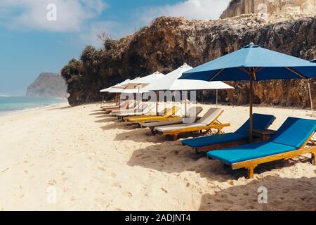 Ponte di Legno sedie con ombrelloni lungo il litorale. Melasti Beach nell'Oceano Indiano. Indonesia Bali. Foto Stock