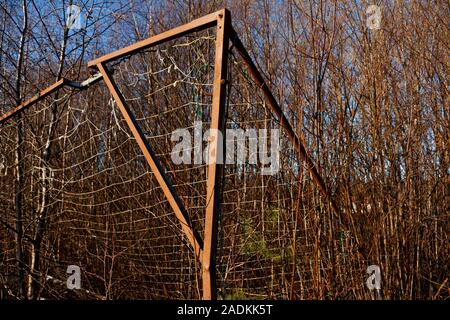 Rotto e arrugginito obiettivo calcio in piedi dal passo vicino alla foresta Foto Stock