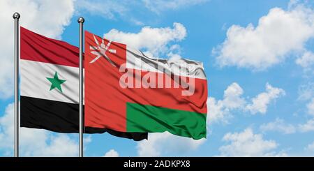 La siria e Oman bandiera sventolare nel vento contro bianco torbido cielo blu insieme. Concetto di Diplomazia e relazioni internazionali. Foto Stock