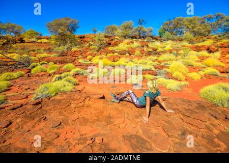 Donna turistica rilassante durante il trekking lungo Arankaia camminare con la macchia mediterranea e il deserto rosso sabbia in Palm Valley, Finke Gorge National Park Foto Stock