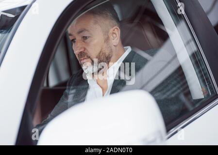 Foto del conducente del veicolo. Grave imprenditore senior alla sperimentazione di nuove auto Foto Stock