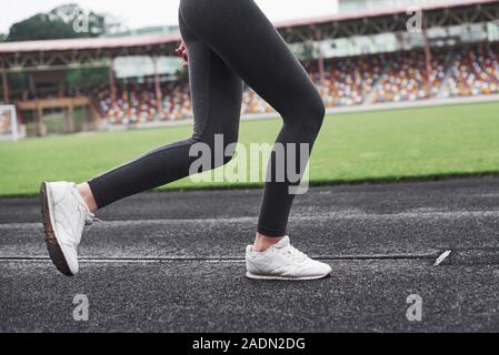 Immagine del soltanto sulle gambe. Ragazza che corre sulla pista dello stadio di giorno Foto Stock