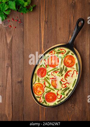 La cucina italiana tradizionale, frittata con verdure in una ghisa pan. Il layout verticale, vista dall'alto, uno spazio vuoto per il testo Foto Stock