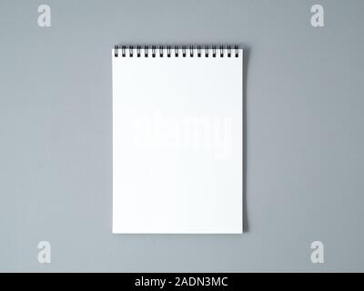 Foglio bianco di un notebook con una spirale su un grigio neutro sfondo testurizzata Foto Stock