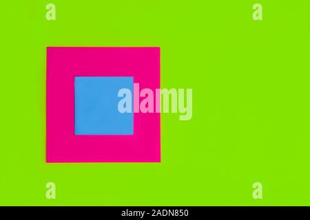 Quadrato bianco blu ciano memo promemoria nota per iscritto le idee e le cose da fare su di una rosa colore fucsia scheda quadrata e di colore verde chiaro sfondo della carta. Foto Stock
