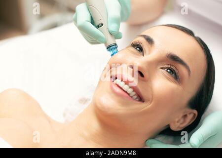 Close up Excited donna godendo di nutrienti della pelle procedura Foto Stock