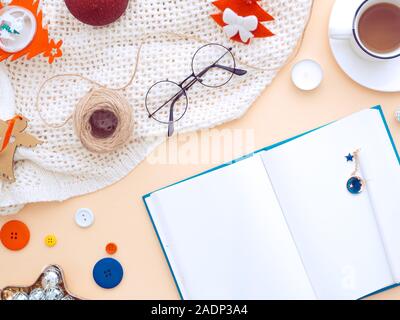 Femmina di Natale scrivania con notebook bianco della carta. Decorazione di natale sul posto di lavoro una pesca colore di sfondo. Blogger femminile inverno area di lavoro. L piatto Foto Stock