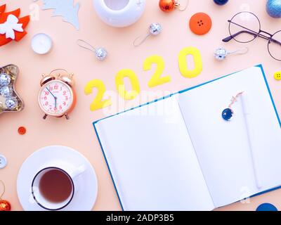 Femmina di Natale scrivania con notebook bianco della carta. Decorazione di Natale workplace su uno sfondo di colore rosa. Blogger femminile inverno area di lavoro. Piatto, laici top Foto Stock