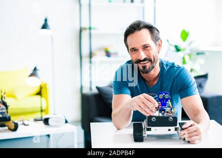 Sorridente uomo adulto tenendo un moderno dispositivo robotico Foto Stock