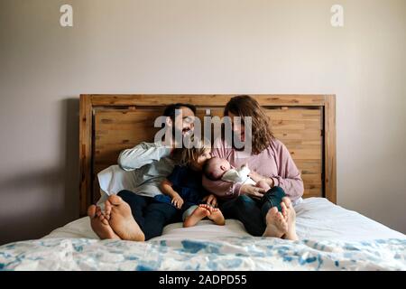 Famiglia con neonati e 4 anni ragazze coccolare insieme sul letto Foto Stock