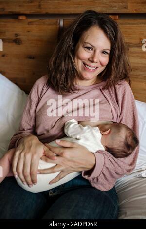 Sorridente inizio-30â€™s mamma Rosa da indossare top Allattamento neonato Foto Stock