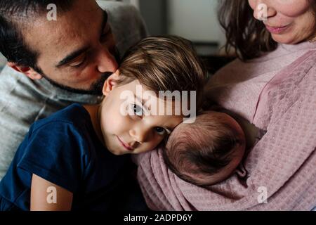 Big Sister appoggia delicatamente la testina sul neonato sorella come papà bacia il Foto Stock