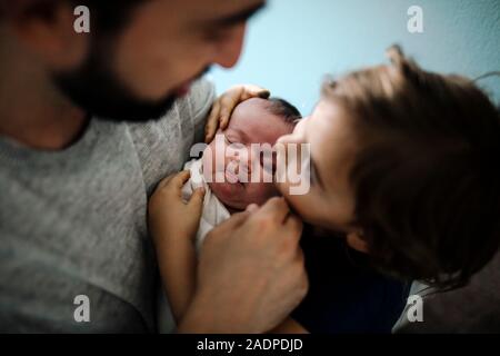 4 anni guardando a papà mentre si tocca la testa di un neonato i gemelli Foto Stock