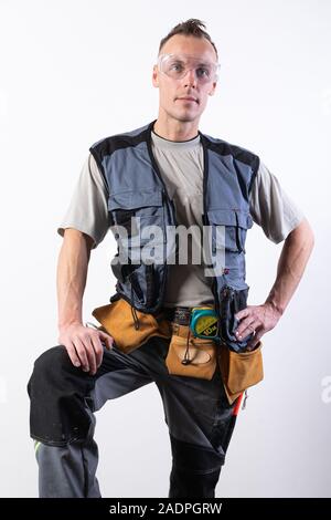 Builder in abiti da lavoro con un attrezzo. Foto Stock