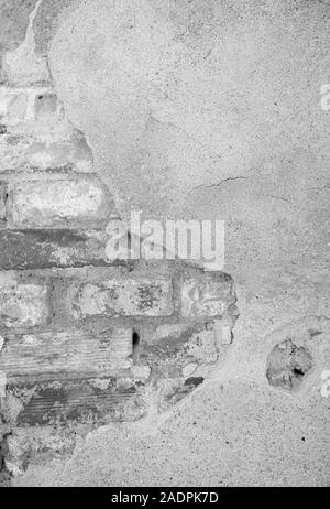 Close-up di un vecchio & danneggiato e muro intonacato. Il gesso è parzialmente distaccata rivelando vecchi mattoni. Alta risoluzione a trama sfondo in bianco e nero Foto Stock