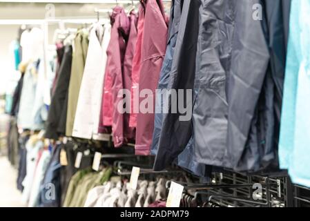 Negozio di abbigliamento. Giacche impermeabili e su store accantonare. Una gamma di capi di abbigliamento con una grande selezione. Foto Stock