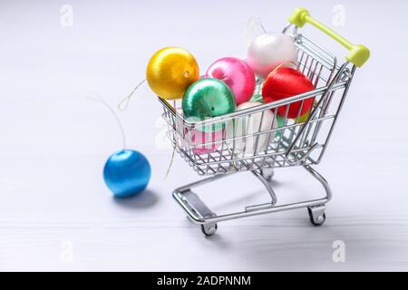 Carrello della spesa e colorato nuovo anno palle su sfondo bianco, creative piana shopping laici, spazio di copia Foto Stock