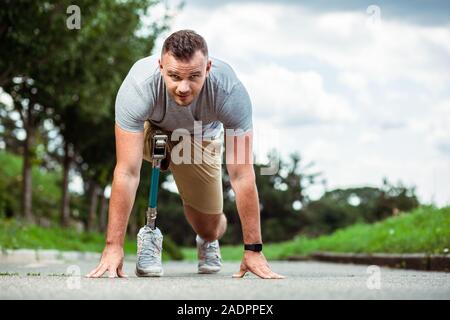 Fiducioso giovane con disabilità permanente sulla pista Foto Stock