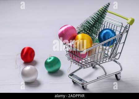 Carrello della spesa e colorato nuovo anno palle su sfondo bianco, l'albero di Natale, piatto shopping laici, spazio di copia Foto Stock