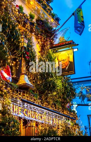 Opulente luci e decorazioni natalizie sulla facciata del Churchill Arms Pub, Londra, Regno Unito Foto Stock