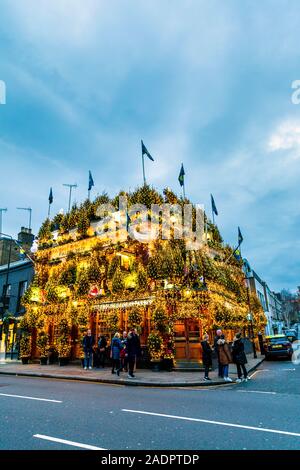 Opulente luci e decorazioni natalizie sulla facciata del Churchill Arms Pub, Londra, Regno Unito Foto Stock