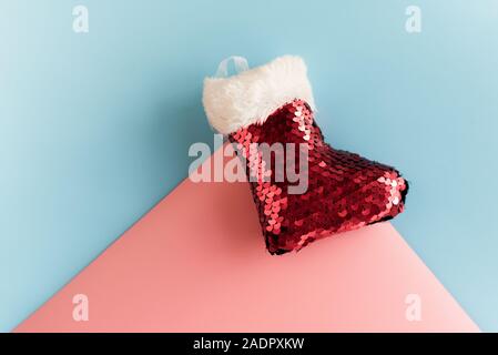 Vacanze a simbolo calza. Rosso calza di Natale. Albero di natale toy su uno sfondo color pastello. Santa calzino in rosa e blu. Foto Stock