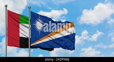 Emirati Arabi Uniti e Isole Marshall bandiera sventolare nel vento contro bianco torbido cielo blu insieme. Concetto di Diplomazia e relazioni internazionali. Foto Stock
