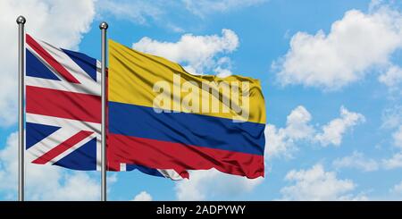 Regno Unito e Colombia bandiera sventolare nel vento contro bianco torbido cielo blu insieme. Concetto di Diplomazia e relazioni internazionali. Foto Stock