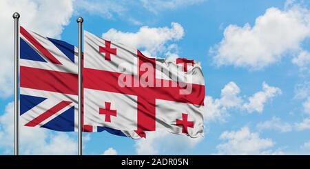 Regno Unito e Georgia bandiera sventolare nel vento contro bianco torbido cielo blu insieme. Concetto di Diplomazia e relazioni internazionali. Foto Stock