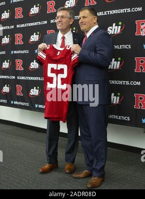 Piscataway, New Jersey, USA. 4° dic, 2019. Rutgers athletic director PATRIC HOBBS tornando capo allenatore di calcio GRED SCHIANO hold up Eric LeGrands' ritirato Jersey durante una conferenza stampa annunciando Schiano il ritorno al centro di Hale in Piscataway, New Jersey. Credito: Brian ramo Prezzo/ZUMA filo/Alamy Live News Foto Stock