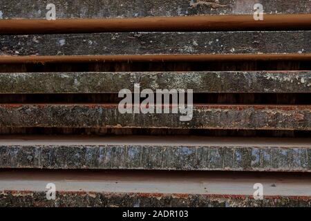 Ripiegate legno marrone e grigio di tavole in una segheria. Impilate le schede ontano come texture. Foto Stock