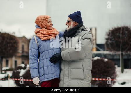 Età matura in cappotti invernali sorridente e avvolgente Foto Stock