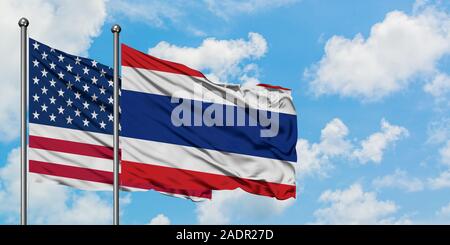 Stati Uniti e la Tailandia bandiera sventolare nel vento contro bianco torbido cielo blu insieme. Concetto di Diplomazia e relazioni internazionali. Foto Stock