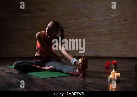 Slim donna la torsione sull'uomo di yoga e guardando lontano Foto Stock