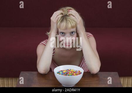 Junge Frau vor einer Schale mit Schokolinsen - Giovane donna nella parte anteriore del recipiente con le lenticchie di cioccolato Foto Stock