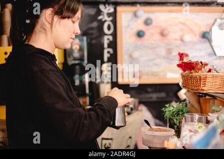 Femmina barista preparazione di caffè mentre in piedi in cafe Foto Stock