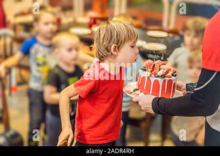 Tempo di soffiare le candele a un bambino festa di compleanno. 6 anno vecchio ragazzo si brucia candele sulla torta Foto Stock
