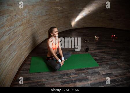 Capelli lunghi donna seduta con le gambe incrociate sul materassino yoga Foto Stock