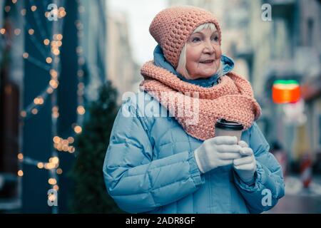 Donna anziana di bere il caffè mentre passeggiate all'aperto Foto Stock