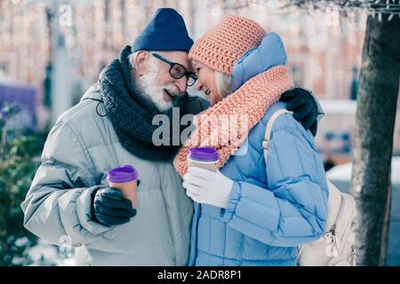 Carino coppia senior abbracciando sotto la struttura ad albero nel giorno di inverno Foto Stock