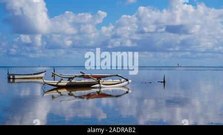 Una canoa outrigger si siede tranquillamente sullo specchio finito di acque di Kaneohe Bay nelle Hawaii Foto Stock