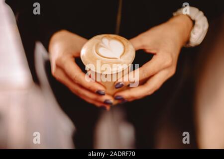 Immagine ritagliata di mani femminili holding tazza monouso di caffè Foto Stock