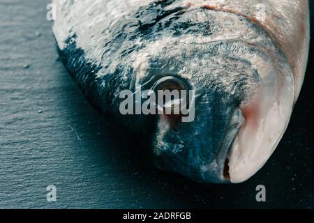 Pulire il pesce crudo testa sulla superficie scura Foto Stock