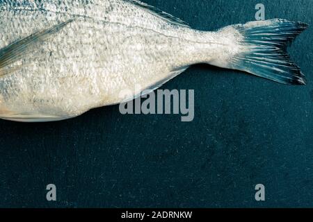 Pesce crudo con liscio pulito del corpo sulla tavola nera Foto Stock