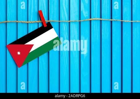 Bandiera della Giordania appesi stendibiancheria attaccato con clothespins in legno su aqua blu sullo sfondo di legno. Giornata nazionale del concetto. Foto Stock