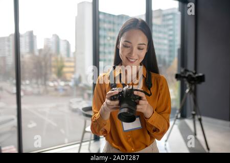 Dai capelli scuri carino giovani reporter a guardare le foto nella fotocamera Foto Stock