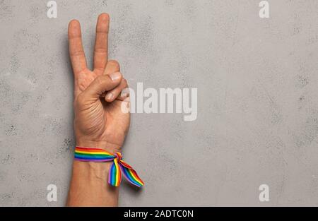 Simbolo di pace e di vittoria da due dita. Sfondo grigio. LGBT nastro arcobaleno orgoglio. Copia spazio per il testo Foto Stock