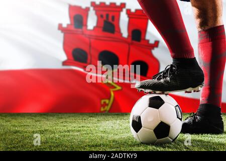 Close up gambe di Gibilterra football team player in rosso calzini, scarpe sul pallone da calcio al calcio di punizione o spot pena giocare sull'erba. Foto Stock