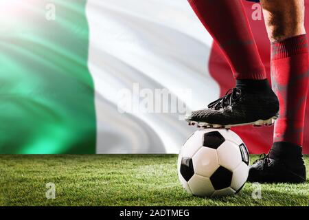 Close up gambe di Italia football team player in rosso calzini, scarpe sul pallone da calcio al calcio di punizione o spot pena giocare sull'erba. Foto Stock